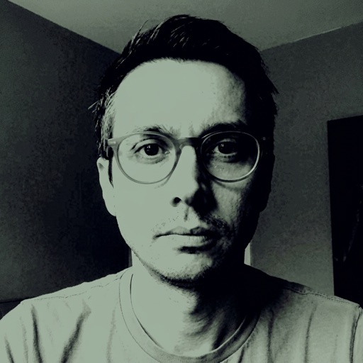plucas — sage-toned portrait of Patrick, glasses, deadpan stare